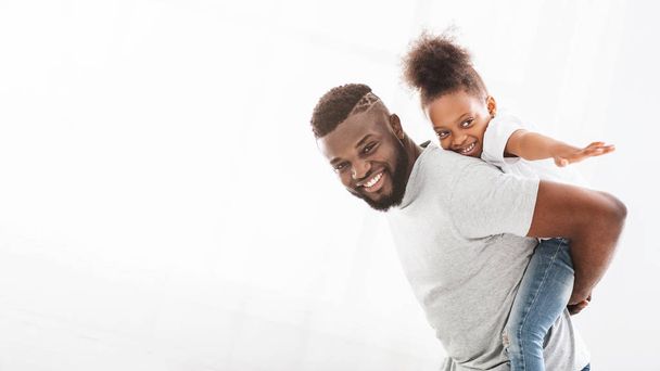Ευτυχισμένος μαύρος πατέρας που κρατάει την κορούλα του ανάσκελα - Φωτογραφία, εικόνα