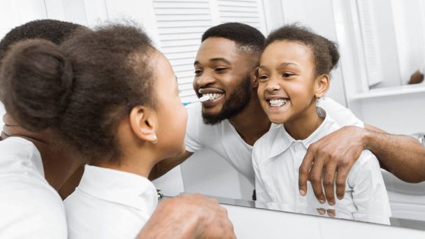 Huomenta. Afro tyttö ja isä harjaus hampaat yhdessä
 - Valokuva, kuva
