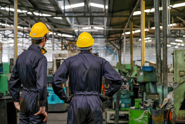 Μαλακή θαμπάδα εικόνα της πλάτης των δύο ανδρών τεχνικός σταθεί και να κοιτάξουμε σε διάφορους τύπους μηχανής στο εργοστάσιο. - Φωτογραφία, εικόνα