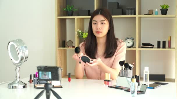4k video van beroemde blogger. Vrolijke vrouwelijke vlogger is het tonen van cosmetica producten tijdens het opnemen van video voor dagelijkse make-up tutorial. op het werk. - Video