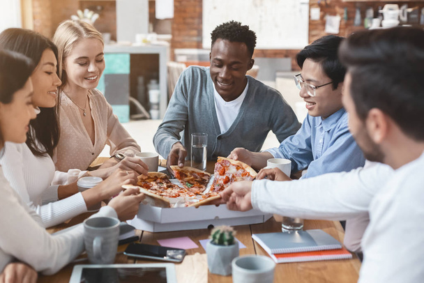 Hungrige junge Arbeitgeber greifen nach Scheiben von Pizza-Lieferungen - Foto, Bild