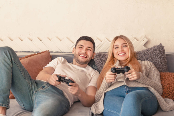 Happy couple holding joysticks and playing video game - 写真・画像