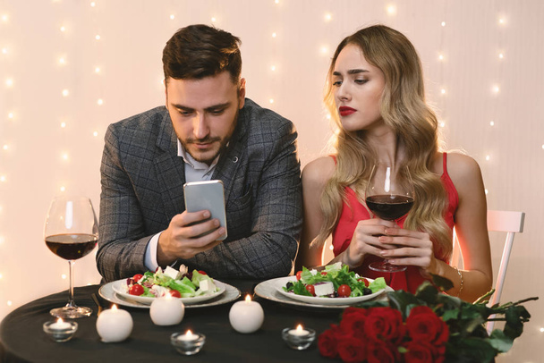 Žárlivá žena Pekking do přítele Smartphone během večeře v restauraci - Fotografie, Obrázek