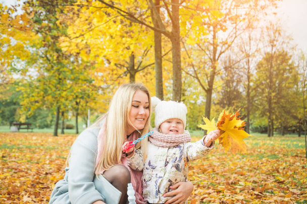 Smiling happy blonde woman and girl hugging outdoor in autumn park, mother and daughter - Foto, Imagen