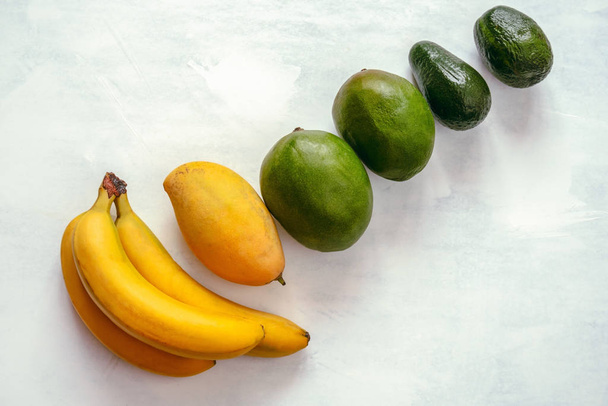 top view fresh tropical fruits row from yellow to green on a white table layout - 写真・画像