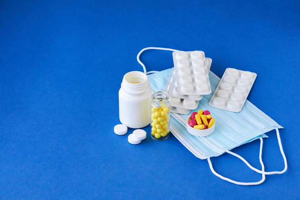 Masques médicaux avec différentes pilules sur fond bleu
                                 - Photo, image