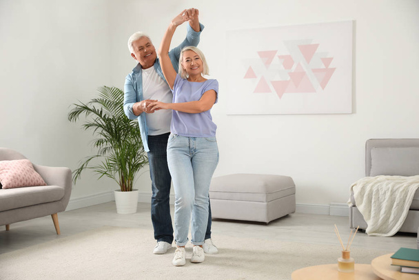 Happy mature couple dancing together in living room - Фото, зображення