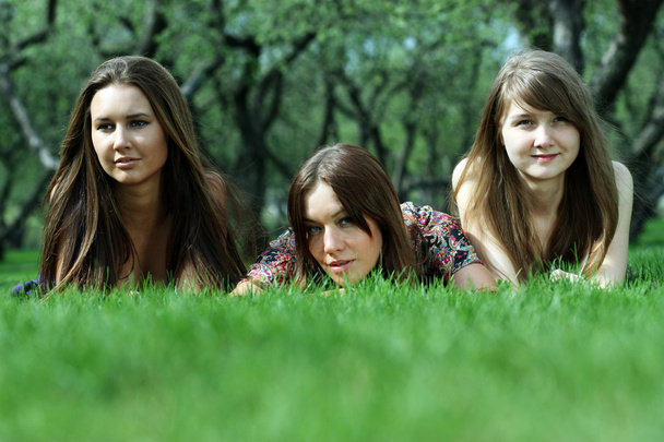 Three young women lying on a green lawn - Photo, image