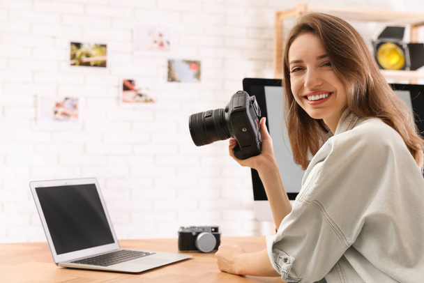 Professional photographer with camera working at table in office - Fotó, kép