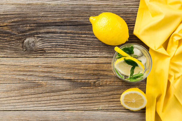 Lemonade or mojito cocktail with lemon and mint with ice. Cold summer refreshing drink decorated with yellow napkin - 写真・画像