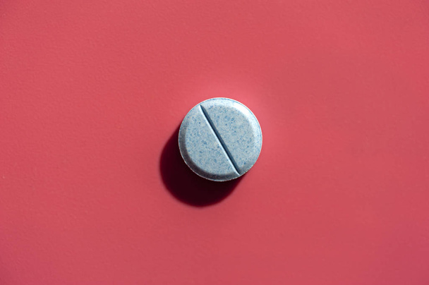 Close-up of one pill lies on a pink surface - Foto, Bild