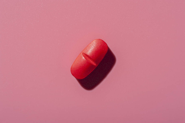 Close-up of one pill lies on a pink surface - Fotoğraf, Görsel