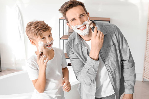 Isä ja poika levittävät partavaahtoa kasvoilleen kylpyhuoneessa.
 - Valokuva, kuva