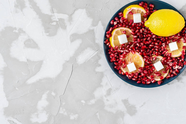 white sugar cubes on a background of red pomegranate seeds and y - Foto, immagini