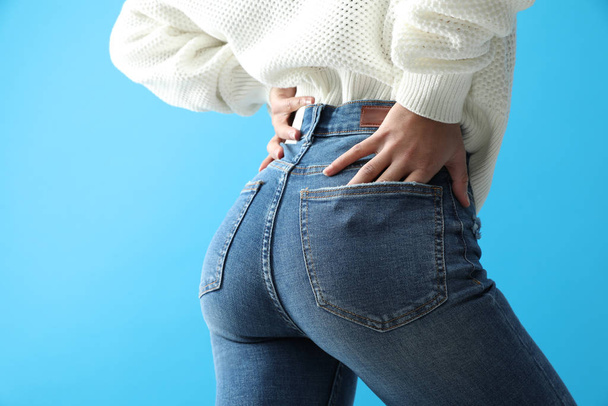 Woman wearing jeans on blue background, closeup - Foto, immagini