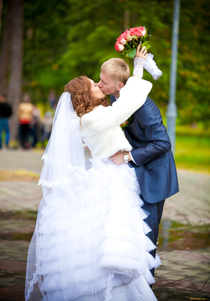 menyasszony vőlegény nyakába átölelve virágokkal - Fotó, kép