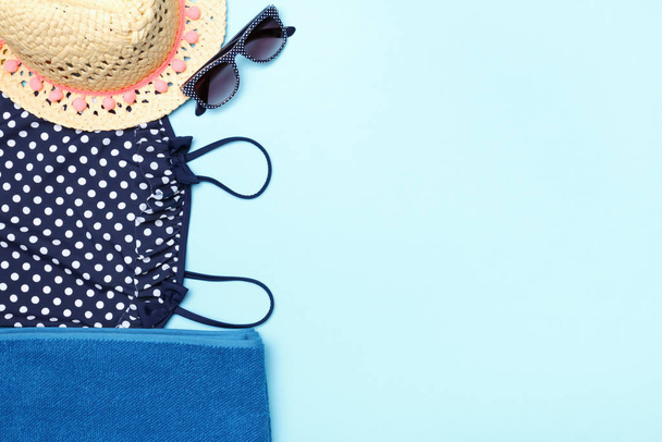 Beach summer female set of clothes and accessories on a blue background. Sunglasses, towel, straw hat and swimsuit. Top view copy space flat lay - Foto, imagen