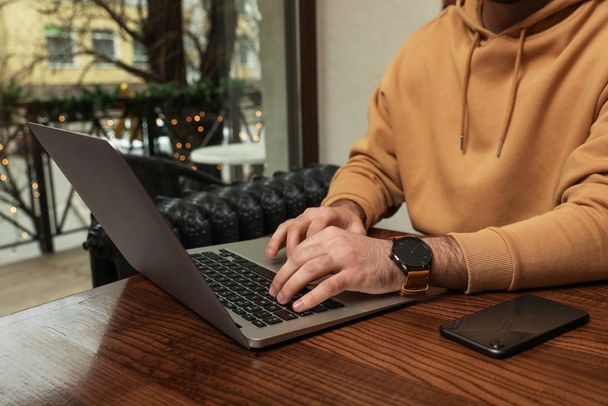 Male blogger working with laptop at table in cafe, closeup - 写真・画像