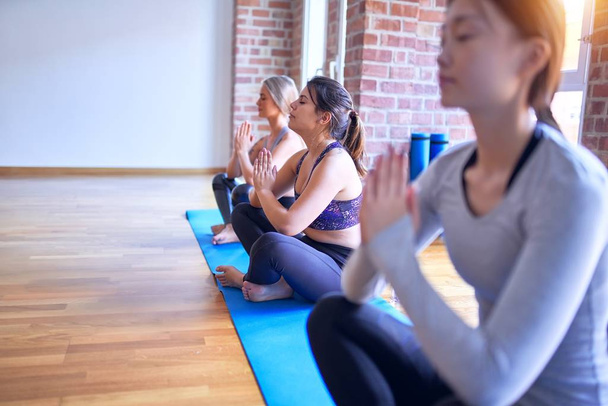 Young beautiful group of sportswomen practicing yoga at gym - Photo, Image