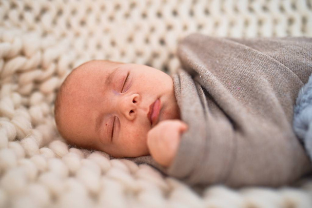 Adorable baby lying down on the sofa over blanket at home. Newborn relaxing and sleeping comfortable - Foto, imagen