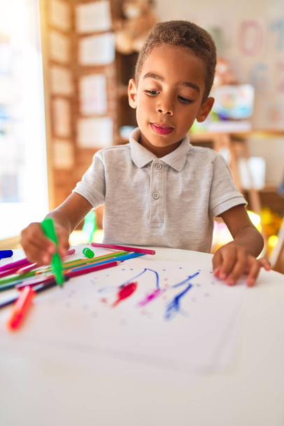Gyönyörű afro-amerikai kisgyermek rajz papírral és filctollal az óvodában - Fotó, kép