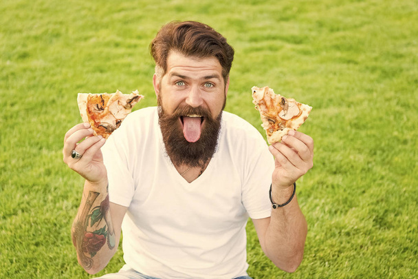 Best food ever. Man bearded hipster eating delicious pizza. Hungry greedy man hold pizza in both hands. Cheerful guy eat pizza. Summer picnic concept. Caucasian male loving Italian traditional food - Valokuva, kuva