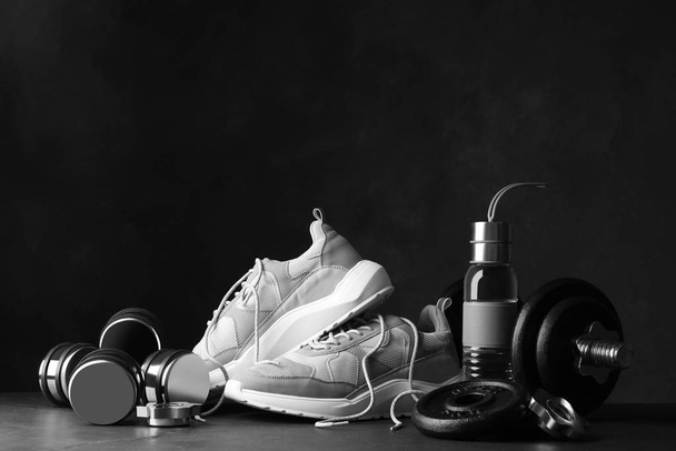 Gym equipment and accessories on stone floor against dark background - Foto, imagen