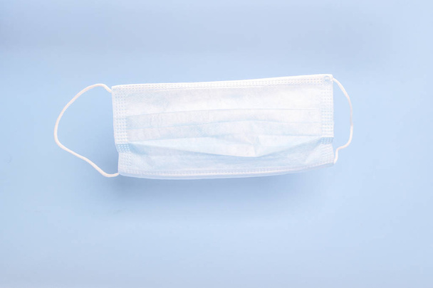 Máscara médica com alças de borracha no fundo azul. Conceito de proteção contra bactérias
. - Foto, Imagem