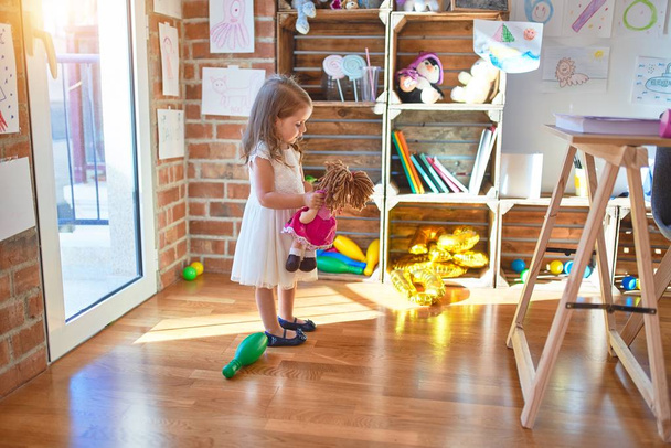 Adorable niño rubio jugando alrededor de un montón de juguetes en el jardín de infantes
 - Foto, imagen