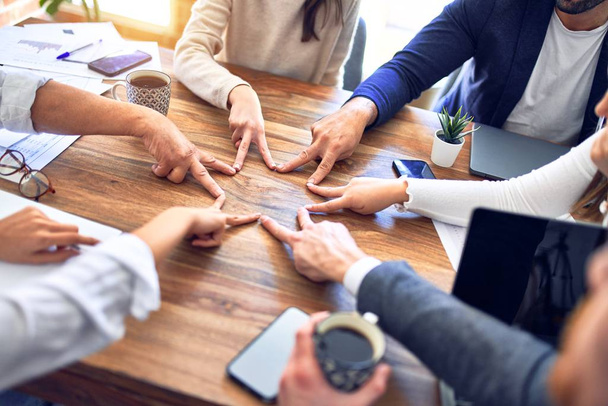 Skupina podnikatelů stojí s rukama u sebe. Dělat symbol s prsty v kanceláři - Fotografie, Obrázek