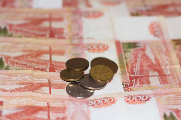 Ruské peníze. Bankovky o pěti tisících rublech a železných mincích, měděné a lesklé. Fotografie v červené a bílé barvě. Pohled shora. Pozadí peněz - Fotografie, Obrázek