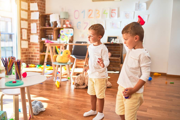 Schattige blonde tweeling spelen rond veel speelgoed op de kleuterschool - Foto, afbeelding