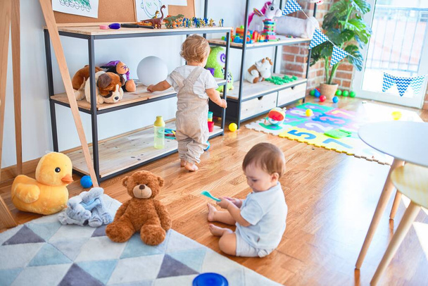 Beautiful toddlers playing around lots of toys at kindergarten - Photo, Image