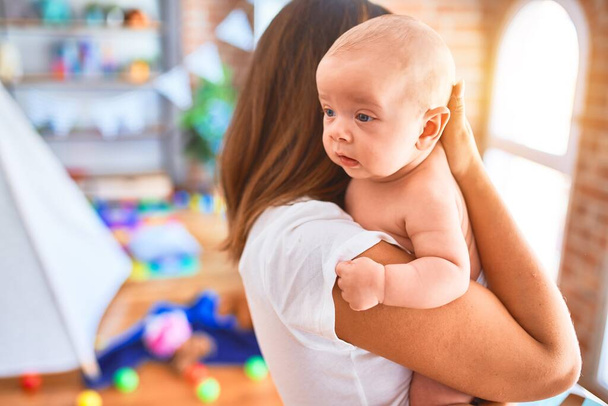 Mladá krásná žena a její dítě stojí doma. Matka drží a objímat novorozence - Fotografie, Obrázek