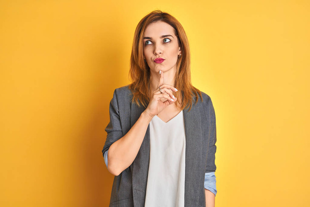 Redhead caucasian business woman over yellow isolated background doing funny gesture with finger over head as bull horns - Фото, изображение