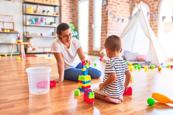 Hermoso maestro y niño jugando con bloques de construcción torre de construcción en el jardín de infantes
 - Foto, Imagen