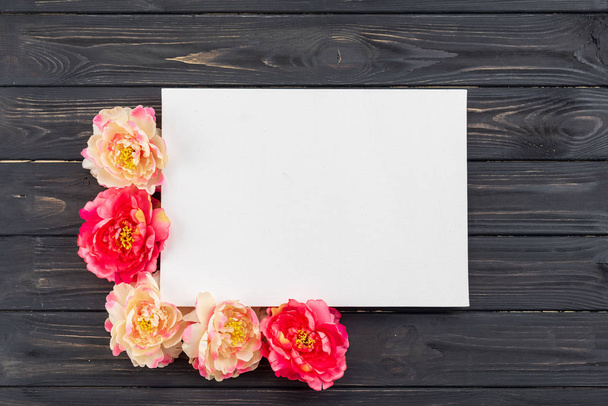 Peonies and white sheet of paper on a dark wooden background - Photo, Image