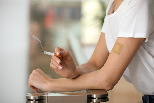 Young woman with nicotine patch and cigarette indoors, closeup - Фото, изображение