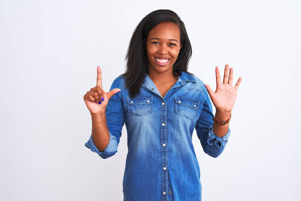 Mooi jong Afrikaans amerikaans vrouw dragen denim jas over geïsoleerde achtergrond tonen en wijzen met vingers nummer zeven terwijl glimlachen zelfverzekerd en gelukkig. - Foto, afbeelding