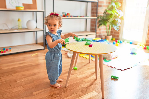 Beautiful caucasian infant playing with toys at colorful playroom. Happy and playful at kindergarten. - Foto, imagen