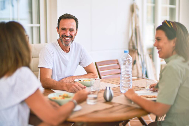 Beautiful family sitting on terrace eating foods speaking and smiling - Photo, Image