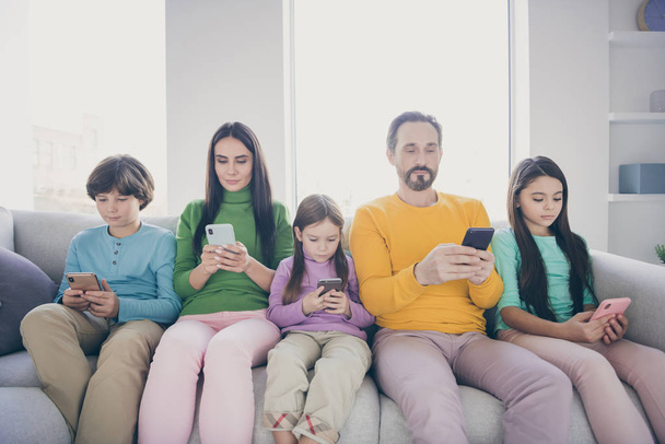 Portrait of nice attractive lovely charming big full focused family pre-teen kids sitting on divan using 5g app blogging post smm media browsing web service at light white interior style house - 写真・画像