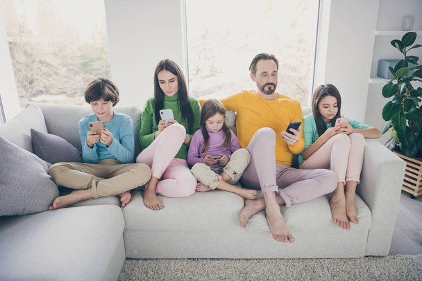 Portrait of nice attractive bare foot big full focused family pre-teen kids sitting on divan using 5g app internet online wi-fi connection browsing surfing at light white interior style house - Foto, Bild