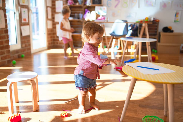 Güzel bebekler gülümseyerek anaokulunda bir sürü oyuncakla oynayarak mutlu olurlar. - Fotoğraf, Görsel