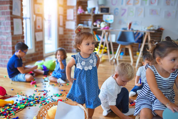 Adorable group of toddlers playing around lots of toys at kindergarten - Photo, Image