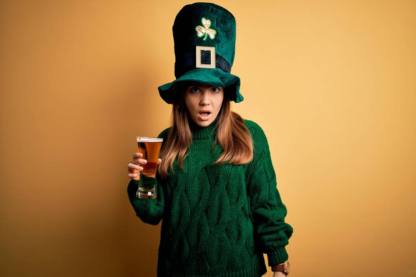 Aziz Patrick Günü 'nde yeşil şapkalı, bira içen genç bir kadın. Şok olmuş, kuşkucu, alaycı ve ağzı açık bir şekilde bakıyor. - Fotoğraf, Görsel