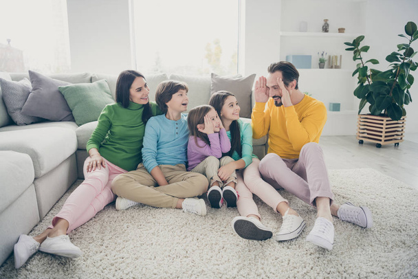 Portrait of nice attractive lovely adorable cheerful cheery friendly family three pre-teen kids sitting on carpet floor playing peekaboo having fun at light white interior style house flat living-room - Photo, Image