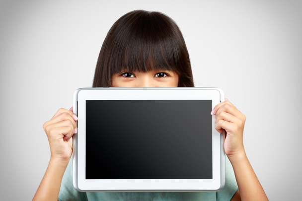 Petite fille tenant vers le haut d'un ordinateur tablette vide obscurcissant le bas
 - Photo, image