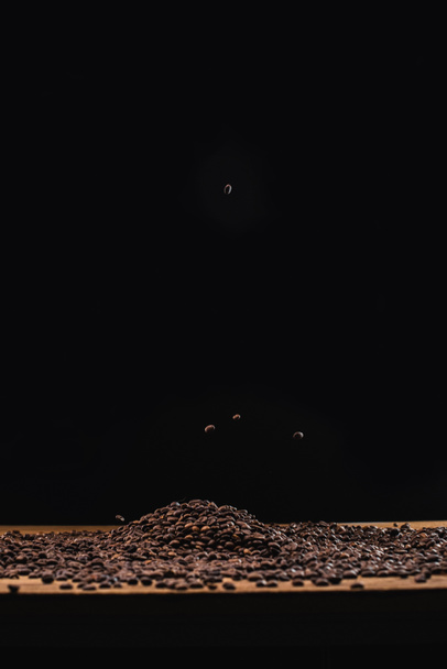 roasted coffee beans in pile isolated on black - Foto, imagen