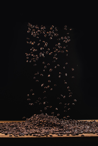 roasted coffee beans in pile and in air isolated on black - Fotó, kép